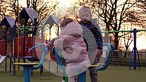 Three little Happy Children having fun spinning on merry-go-round. Smiling Siblings friends playing outside. emotional