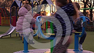 Three little Happy Children having fun spinning on merry-go-round. Smiling Siblings friends playing outside. emotional