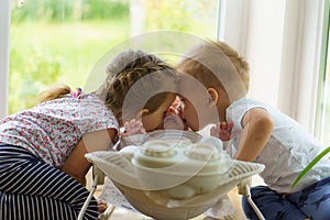 Three little Kids play near the window. Brothers and sister with the baby.Toddler kid meeting newborn sibling. Children