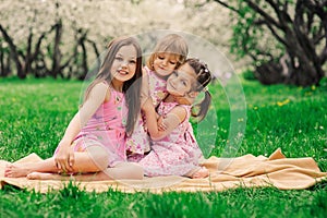 Three little sisters having a lot of fun playing together outdoor in summer park