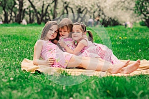 Three little sisters having a lot of fun playing together outdoor in summer park photo