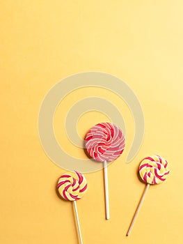 Three lollipops on a yellow background. minimal concept. sugar sweets.