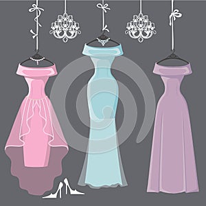 Three long bridesmaid dresses hang on ribbons