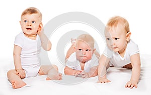 Three looking babies crawl and sit on blanket