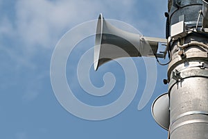 Three loudspeakers on pole against blue sky