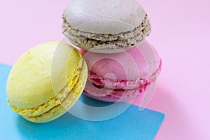 Three macaroons french pastry. Brown, pink and yellow almond cookies