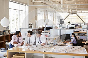 Three male architects in discussion in an open plan office
