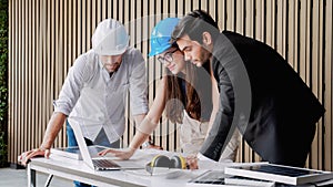 Three male architects in hardhats working together with laptop in concept of discussing project plan solar panels power and then c