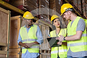 Three male and female warehouse workers are working in a warehouse.