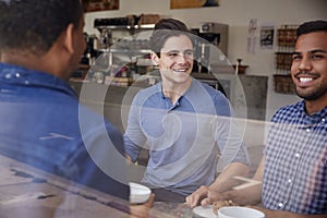 Three male friends having coffee together at a coffee shop
