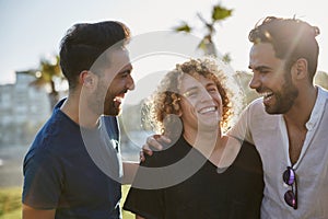 Three male friends standing together outside laughing