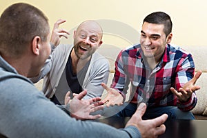 Three male friends talking at home