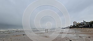 Three man walk when Small ocean waves breaking on beach