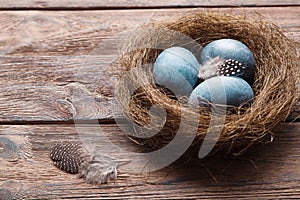 Three marble blue Easter eggs painted by hibiscus, in a nest on a wooden background close-up. The Symbol Of Easter
