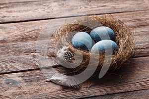 Three marble blue Easter eggs painted by hibiscus, in a nest on a wooden background close-up. The Symbol Of Easter