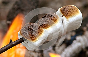 Three marshmallows roating over open camp fire