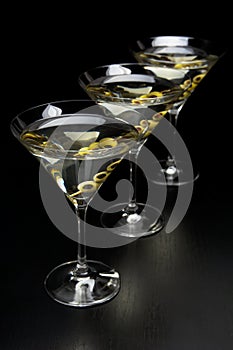 Three Martini drinks with olives isolated on black table