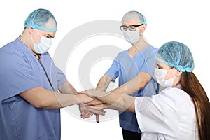 Three masked doctors joined hands in a sign of support and mutual assistance, the concept of medical treatment, insurance, a trade