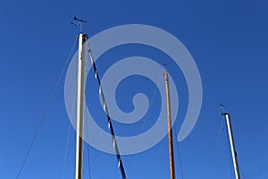 Three Mast Poles of Sailboats from Below and Clear Blue Sky