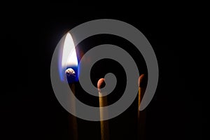 Three matches sticks burning on a black background