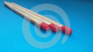 Three matchsticks over blue background. Closeup of matchsticks.