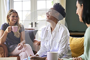 Three Mature Female Friends In Lounge At Home Meeting For A Chat And Hot Drink