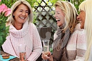 Three mature girlfriends with glasses of sparkling wine