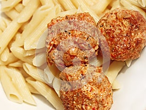 Three meatballs with sauce over pasta