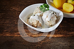 Three meatballs served with a creamy white sauce photo
