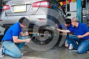 Three mechanic checking wheel and car body at garage, car service technician check and repair customer car at automobile service,