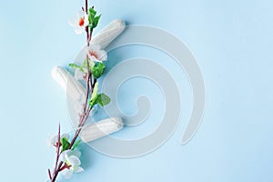 Three medical female cotton swabs on a blue background next to a white flower. Hygienic white tampon for women. Women`s health