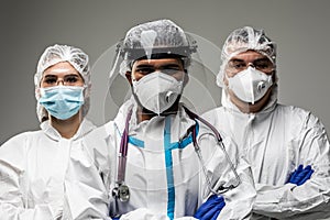 Three medical healthcare workers in biohazard protective tools standing isolated on gray background. Ready to fight with covid19