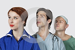 Three medical practitioners looking away against gray background