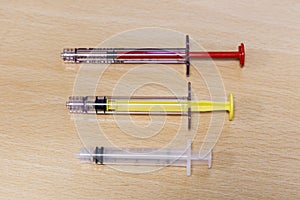 Three Medical Syringes of Different Colors and Size