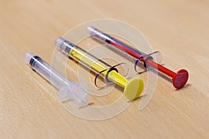 Three Medical Syringes of Different Colors and Size