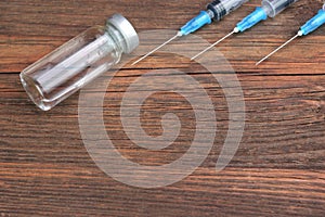 Three Medical Syringes And Vial On Rough Wood Board