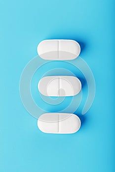 Three medicinal tablets in a row on a blue background, isolate