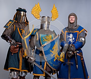 Three medieval knights in full armor standing