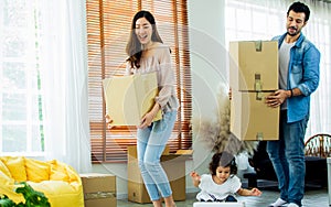 Three members of family, father, mother, little daughter moving to new house or apartment, smiling with happiness, carrying cotton