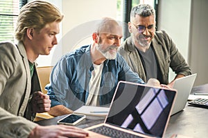 Three Men Analyzing Data on Laptop