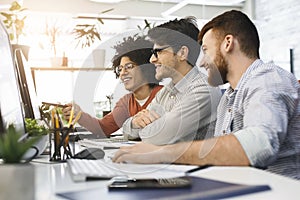 Three men enjoying good coding job on computer at modern office
