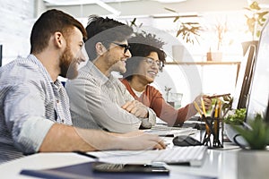 Three men enjoying good coding job on computer at modern office