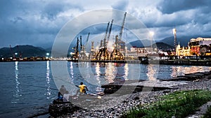 Three men fishing near the cargo port