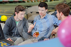 Three men having conversation in bowling center