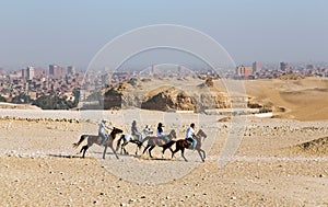 Three men and one woman ride horses to the Pyramids