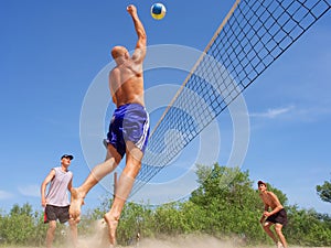 Three men play beach volley