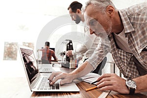 Three men set up a self-made 3d printer to print the form. They check the scribes of the 3d printer on the laptop. photo