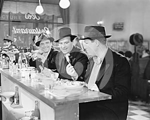 Three men sitting at the counter of a diner photo