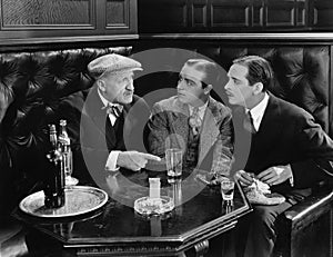 Three men sitting together at a bar photo