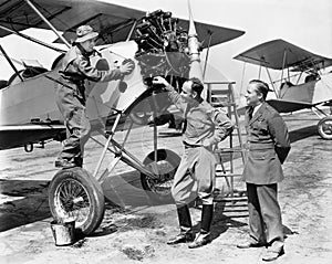 Three men standing next to an aircraft having a conversation